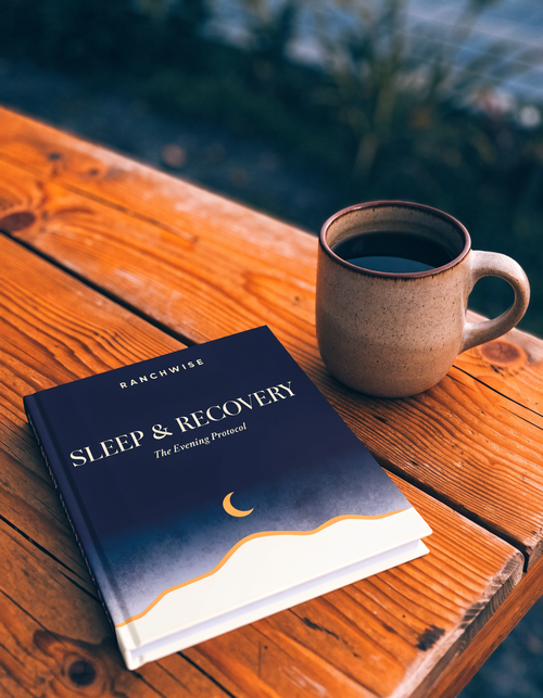 Sleep & Recovery guidebook by RanchWise beside a mug in evening light